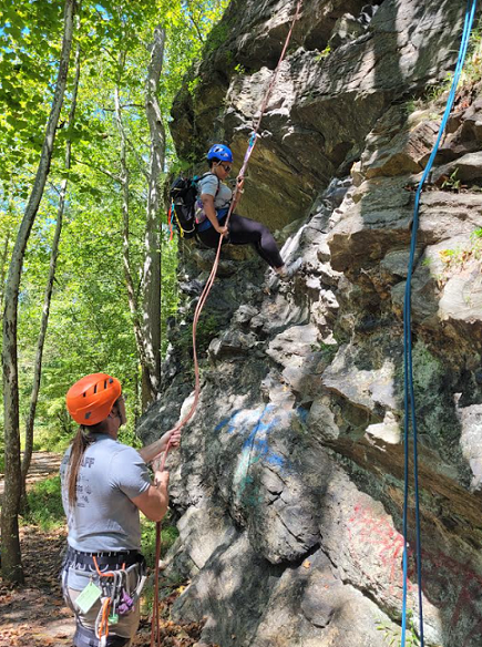 photo of climber rappelling Alberton Rock, with some graffiti shown